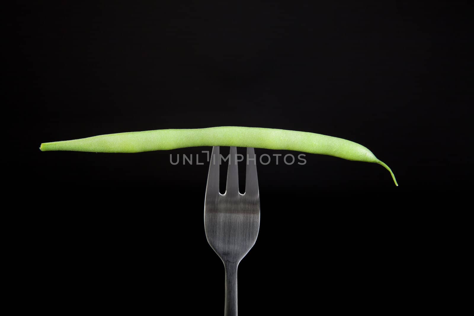 Fresh green bean on fork with black background