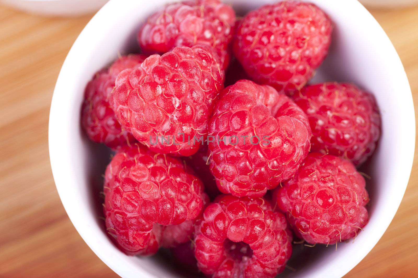 Raspberries in white bowl shot from directly above.