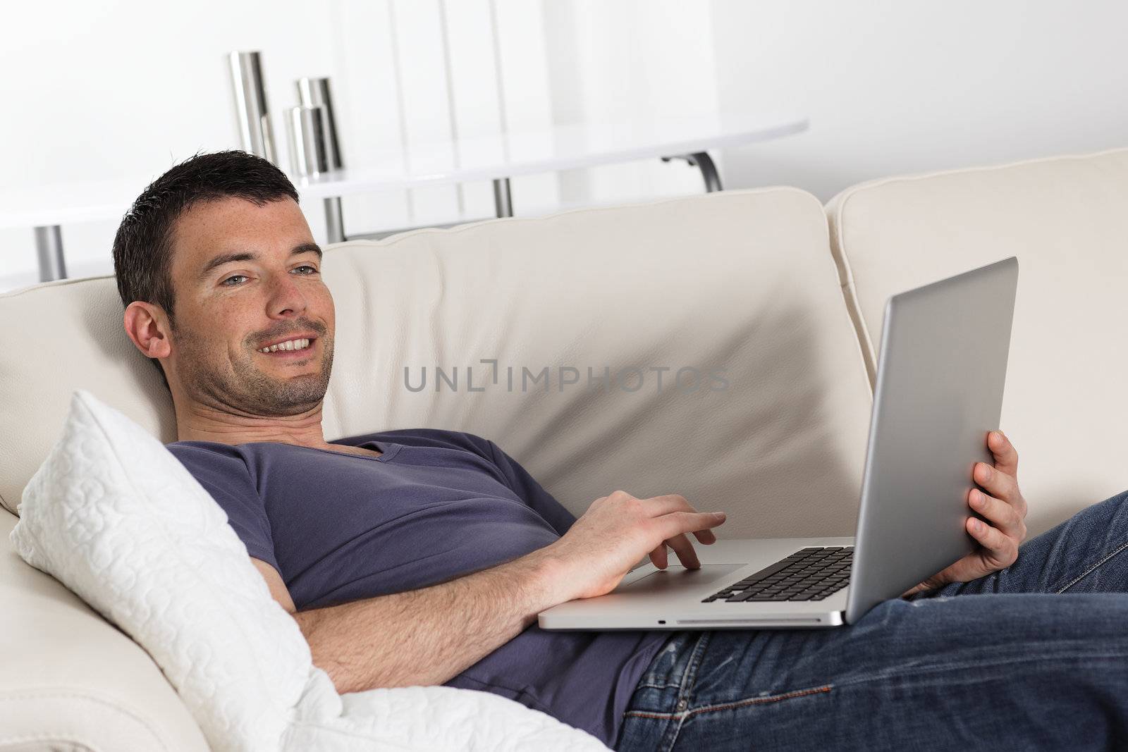 beautiful young man on sofa with computer