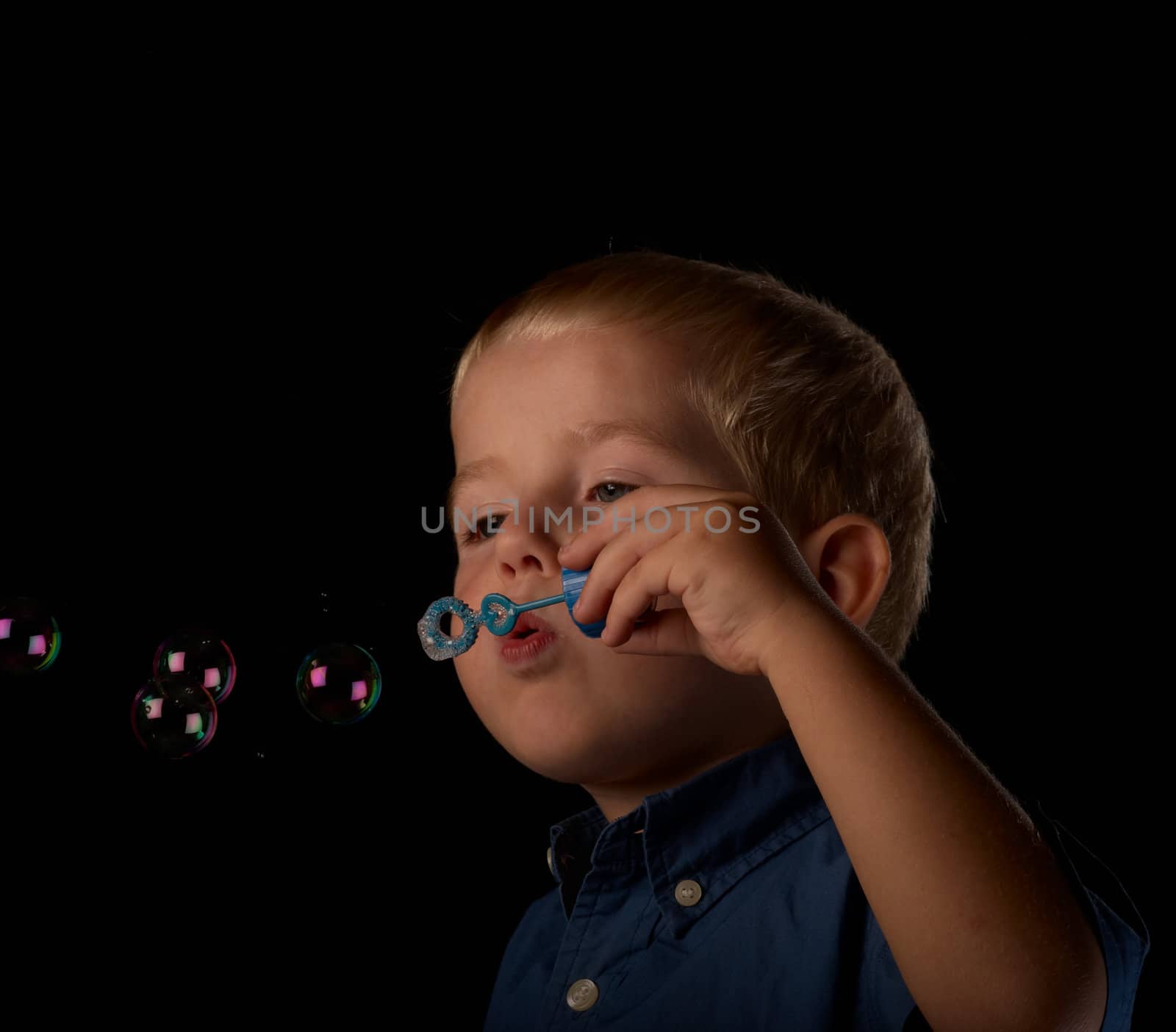 Little blond boy having fun using his bubble wand