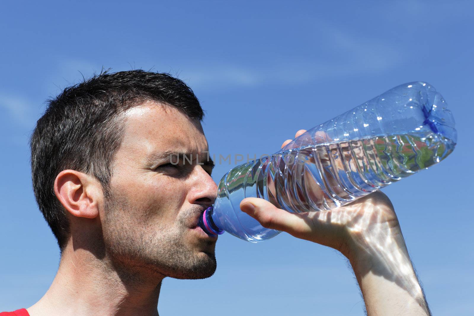 young man drinking water in blue sky