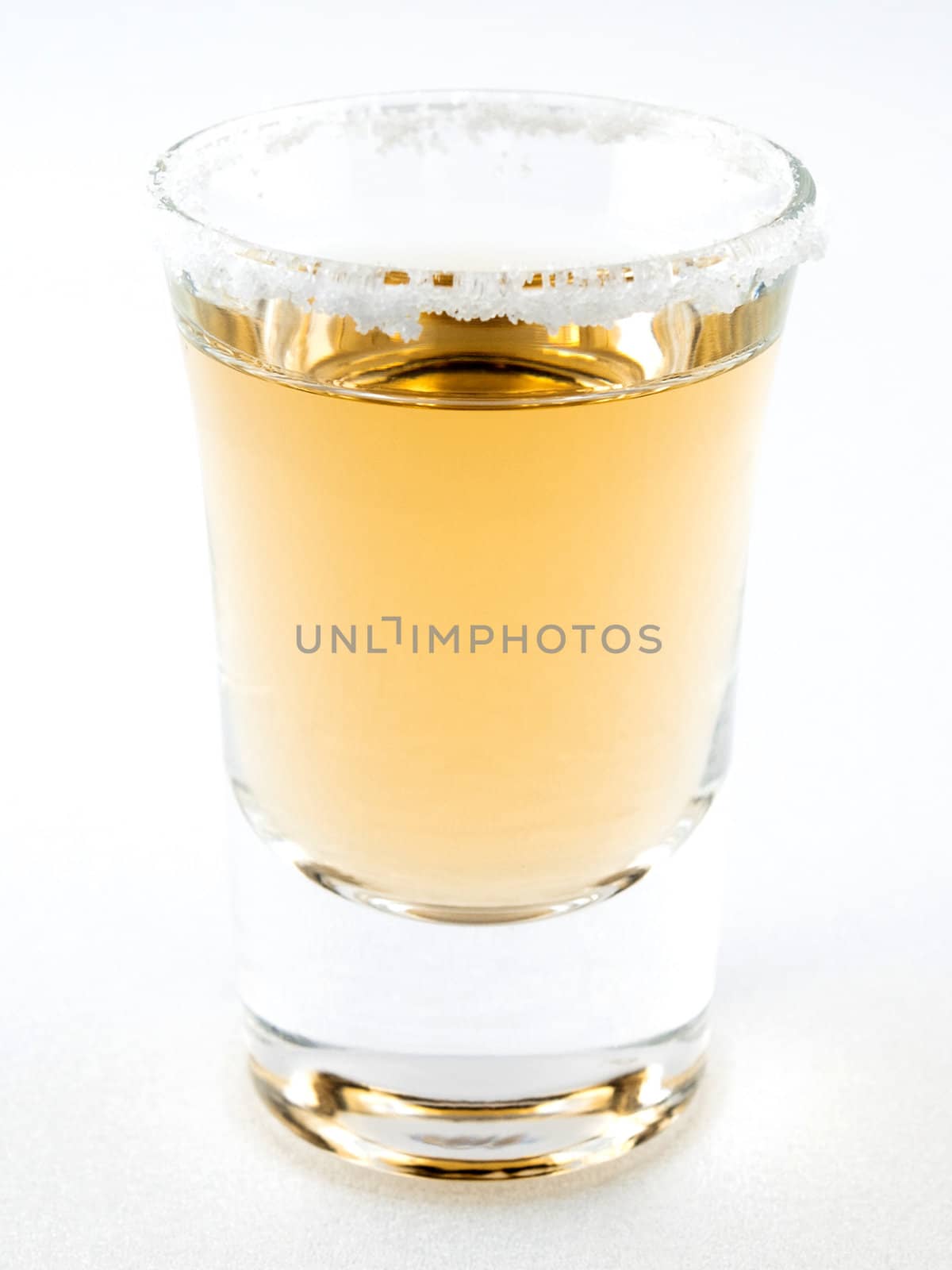 A shot of teqila in a shot glass with a salt rim