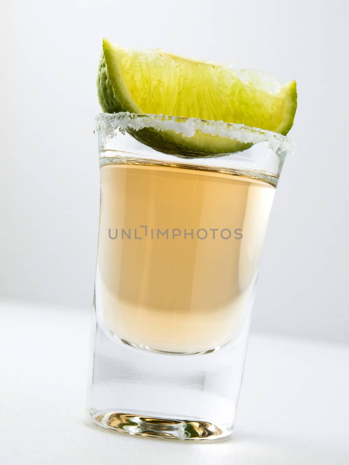A shot of tequila and lime in a shot glass with a salt rim