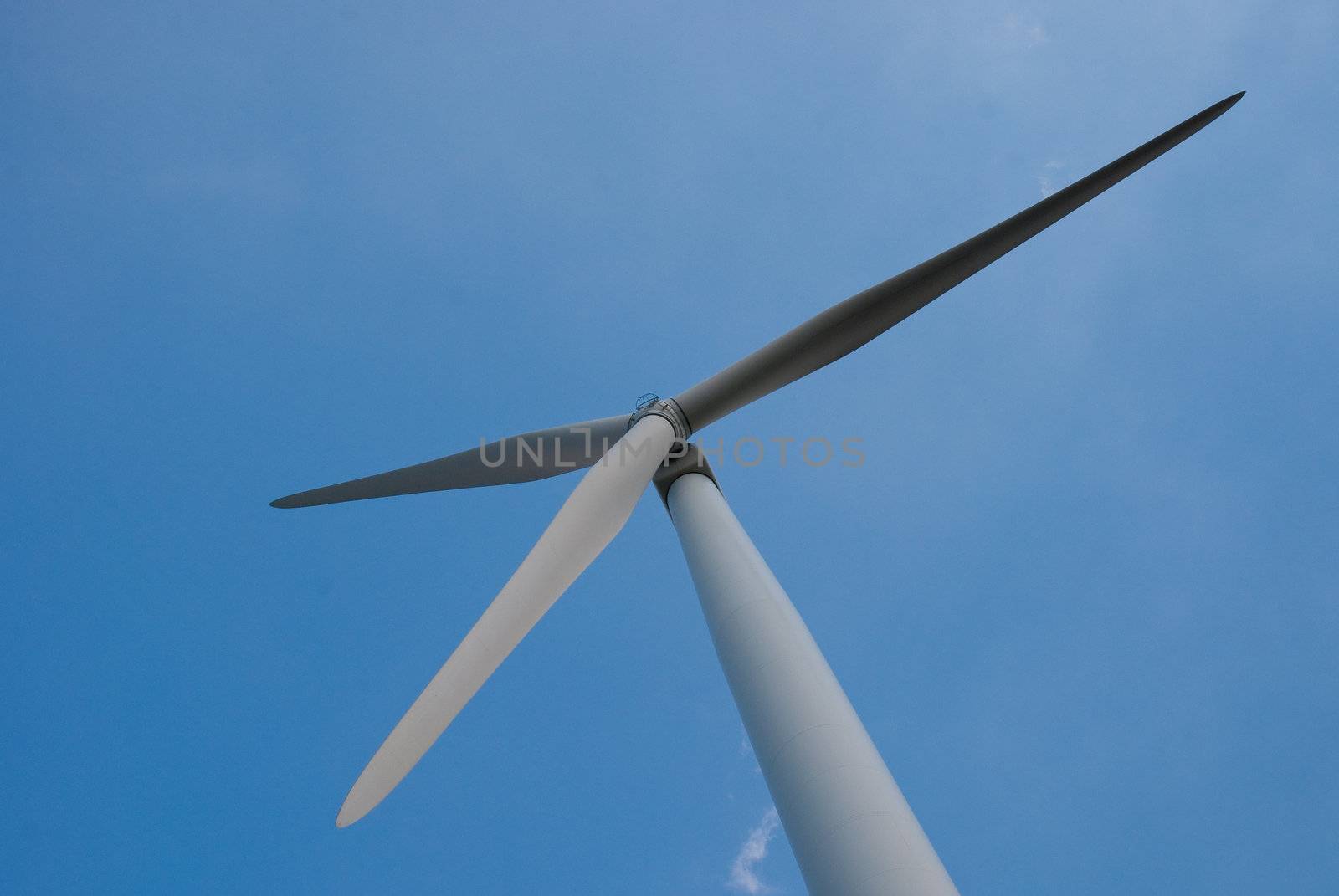 Wind mill power generator against blue clear sky.
