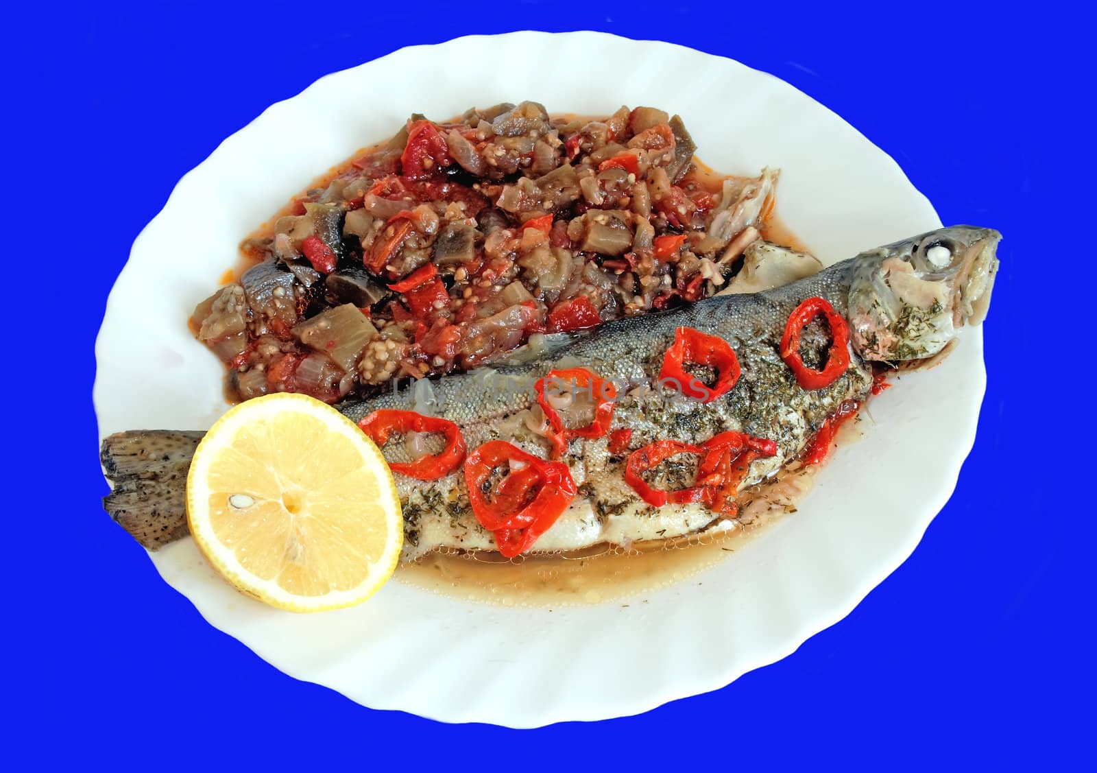 Baked fish with stuffed vegetables over blue background