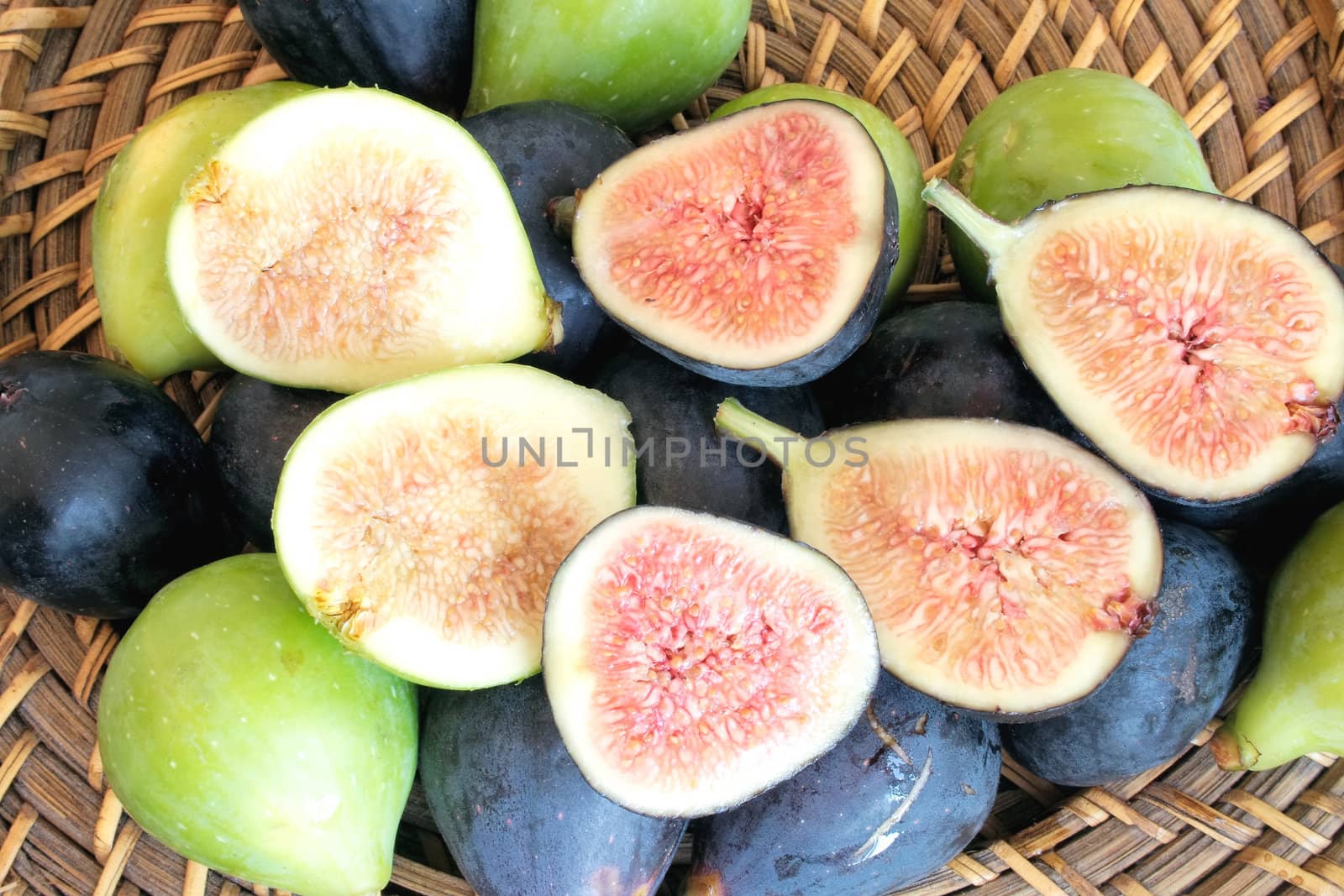 Ripe black and green figs on whicker plate