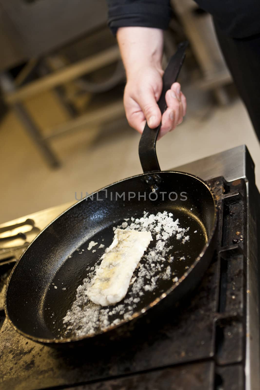 Hand holding a saucepan with fish