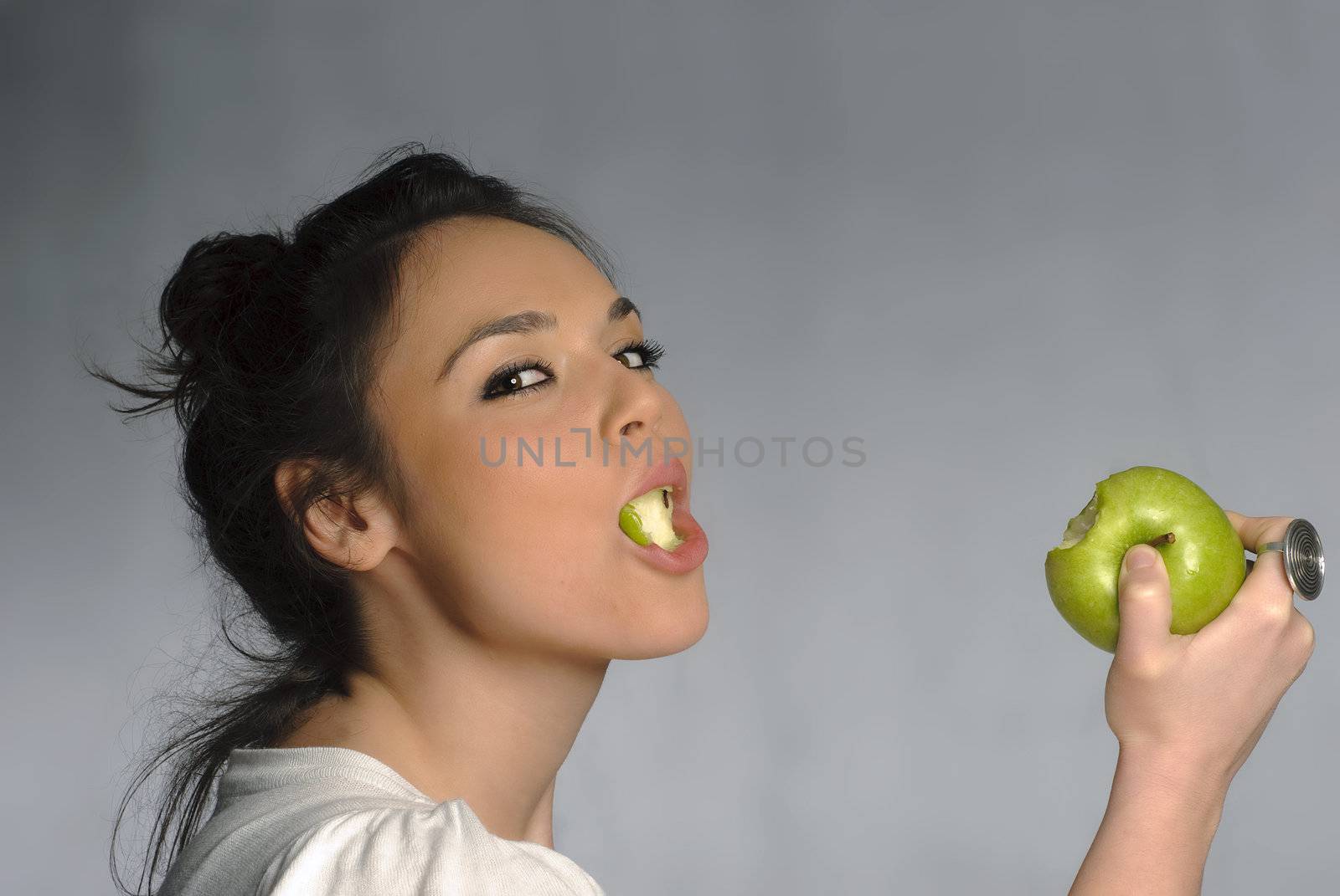 Beautiful young woman with a green apple portrait isolated on gray