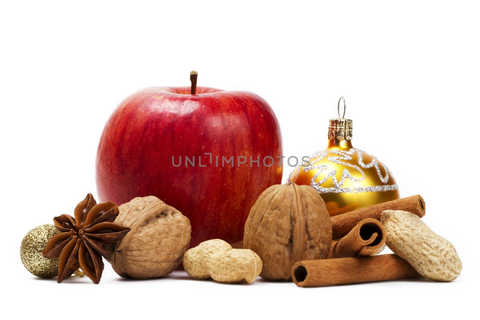 a red apple, star anise, walnuts and peanuts, a christmas ball and cinnamon sticks on white background