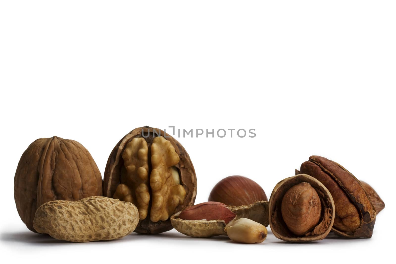 cracked and closed pecans walnuts hazelnuts and peanuts on white background