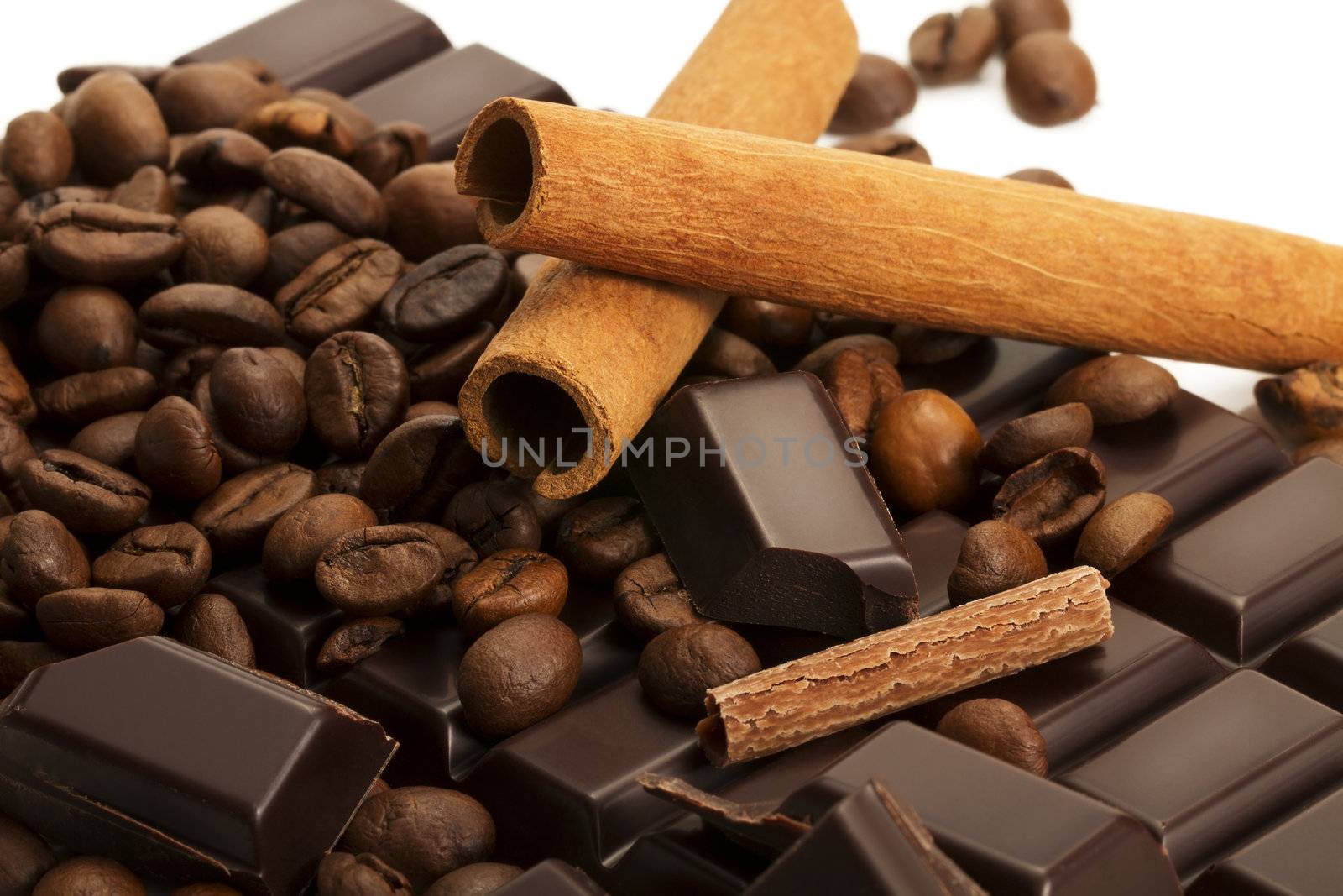 coffee beans with cinnamon sticks and chocolate pieces on a chocolate bar