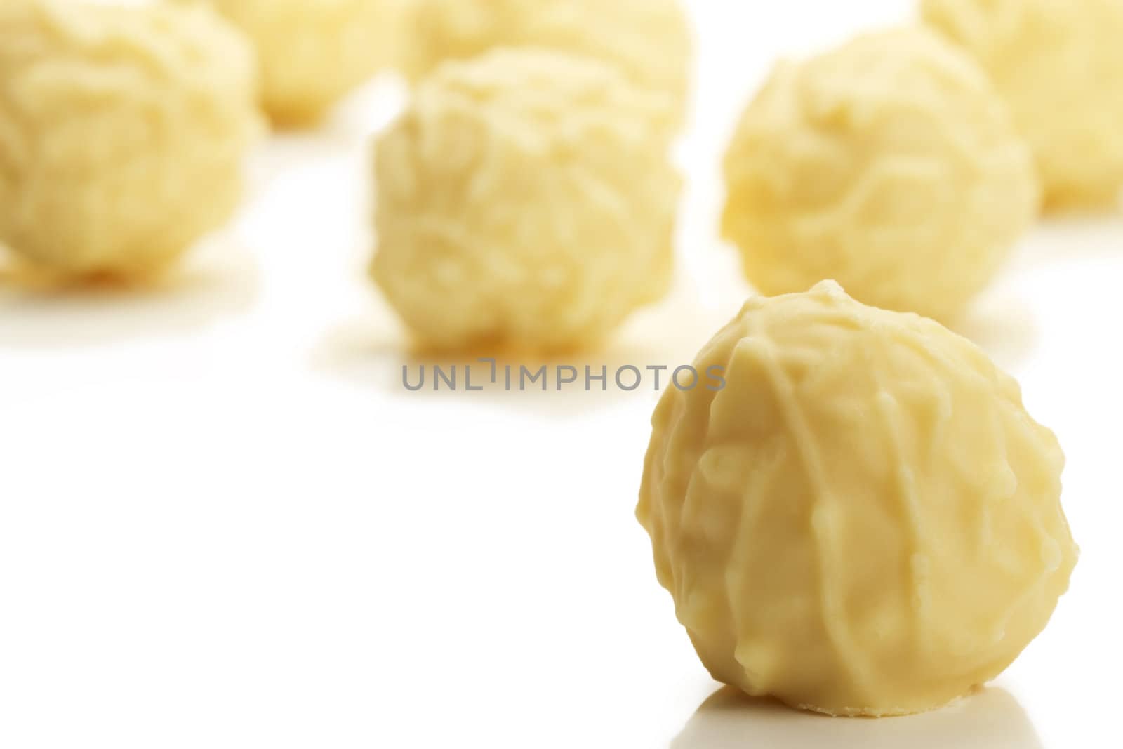 yellow truffle praline in front of many on white background
