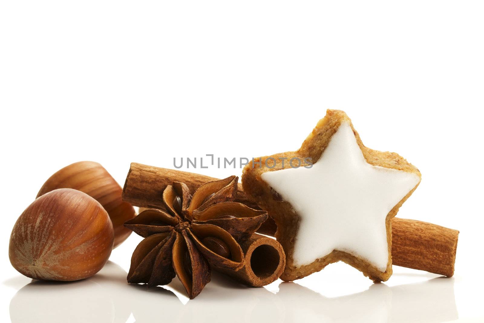 star shaped cinnamon biscuit with cinnamon sticks and hazelnuts on white background