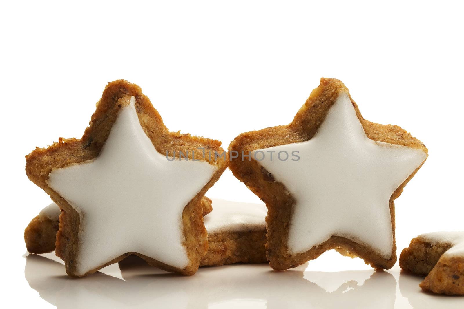 two standing star shaped cinnamon biscuits on white background