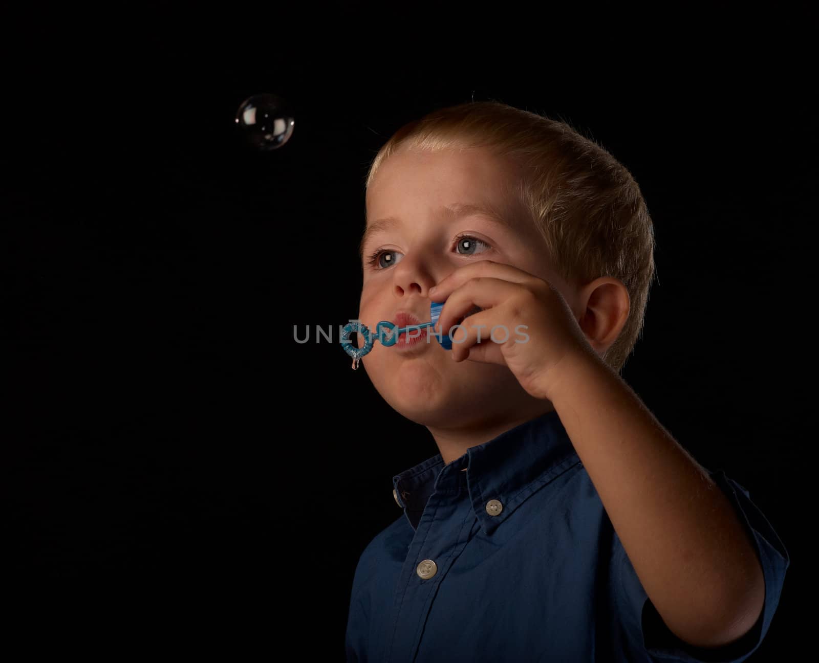 Little boy having fun blowing soap bubbles