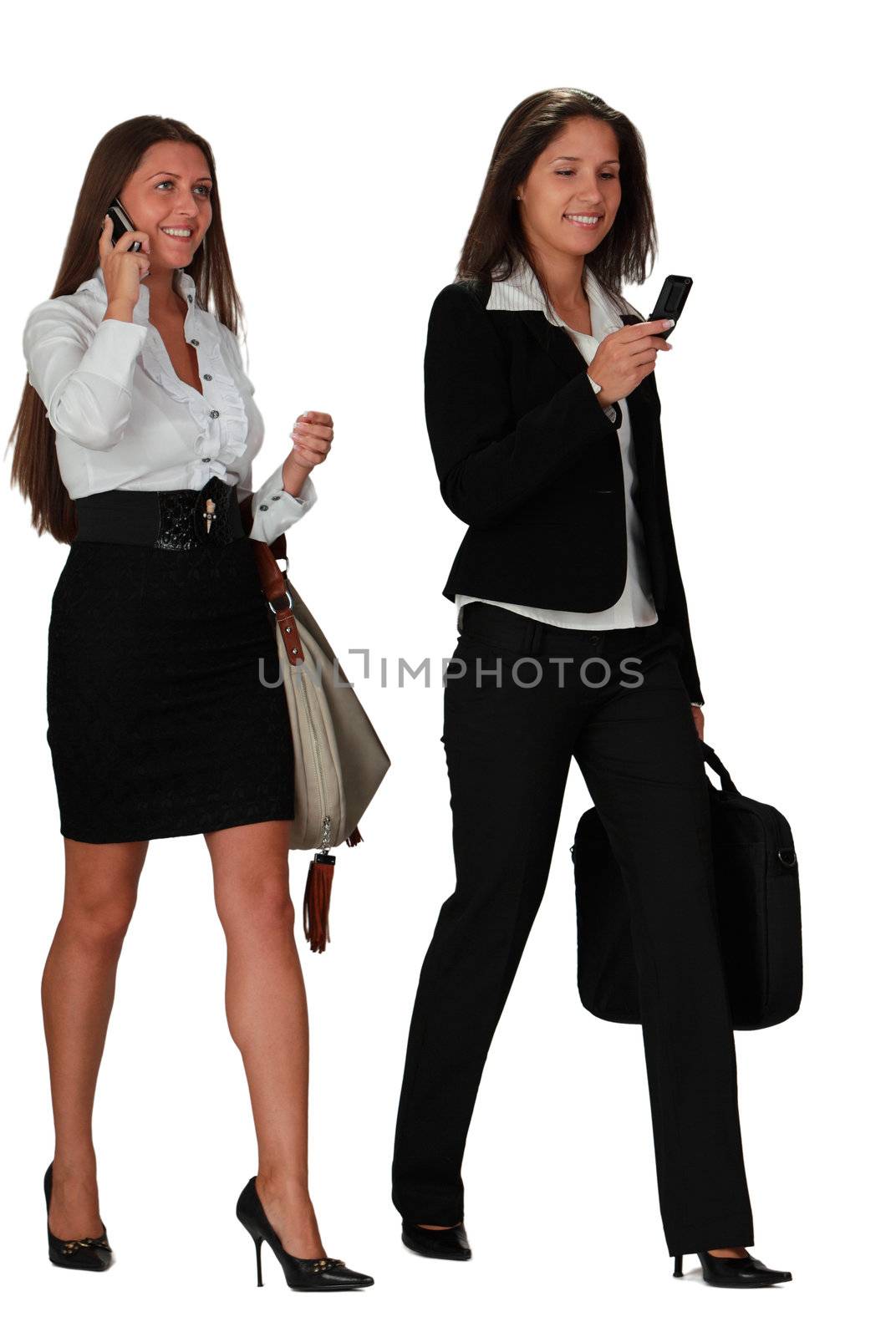 Two young women walking while using mobile phones,isolated against a white background.