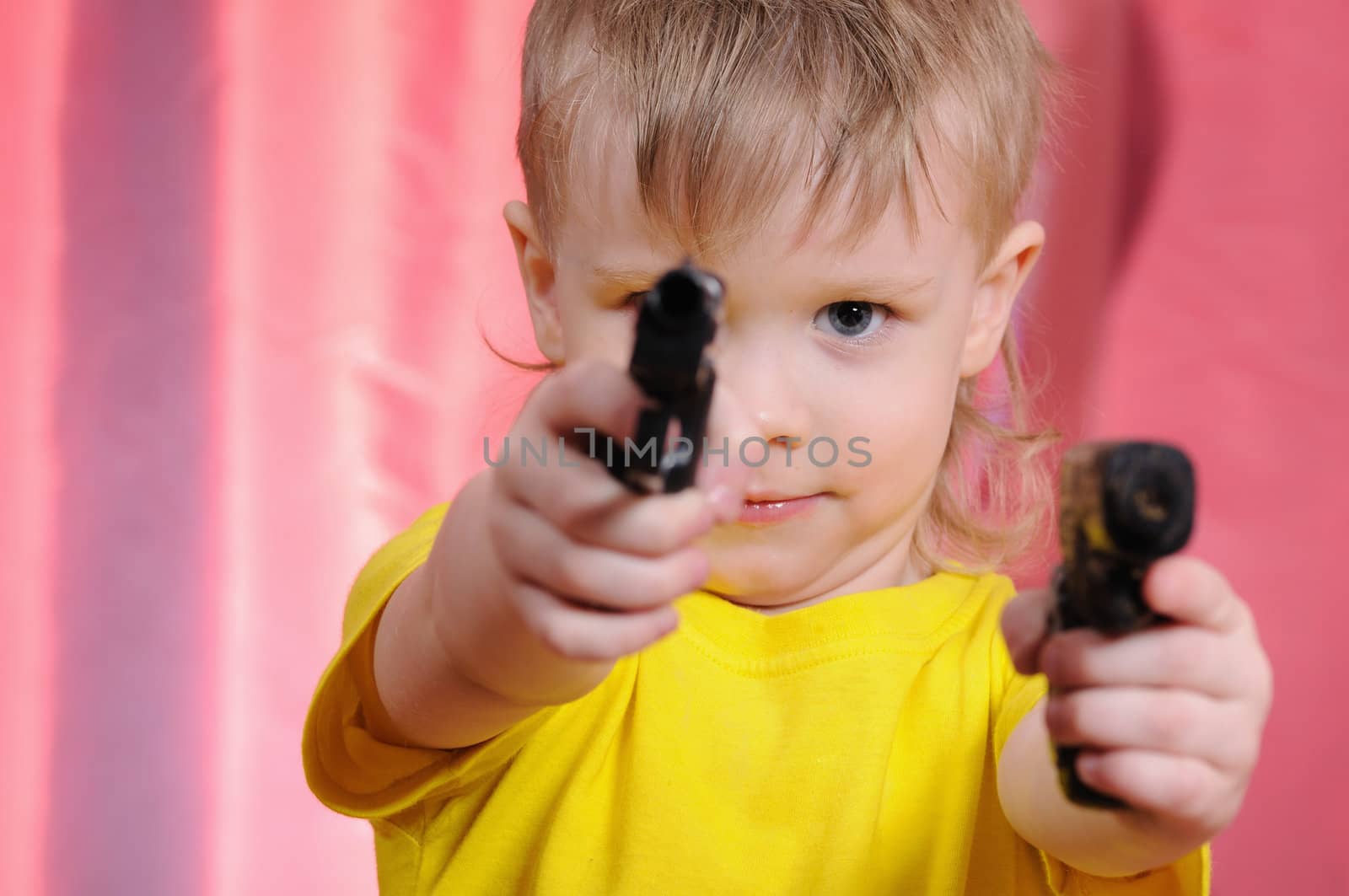 The child in a yellow vest with the weapon