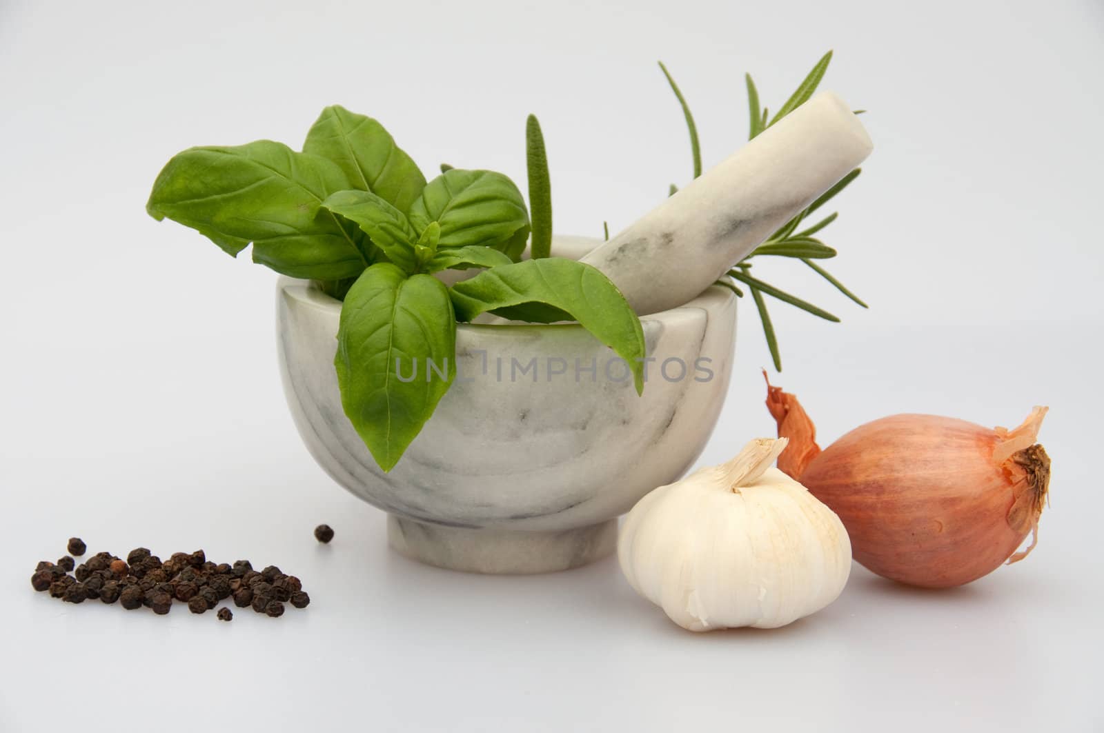 A marble mortar with herbs, garlic, onion and pepper