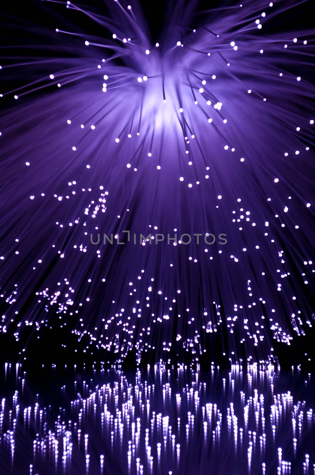Purple fibre optic light strands cascading down against black background and reflecting into the foreground.