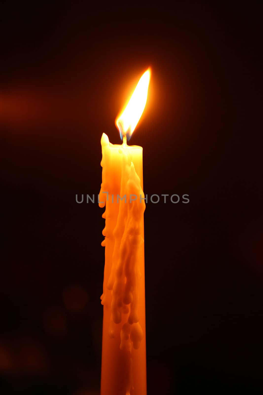 a burning candle in a dark room
