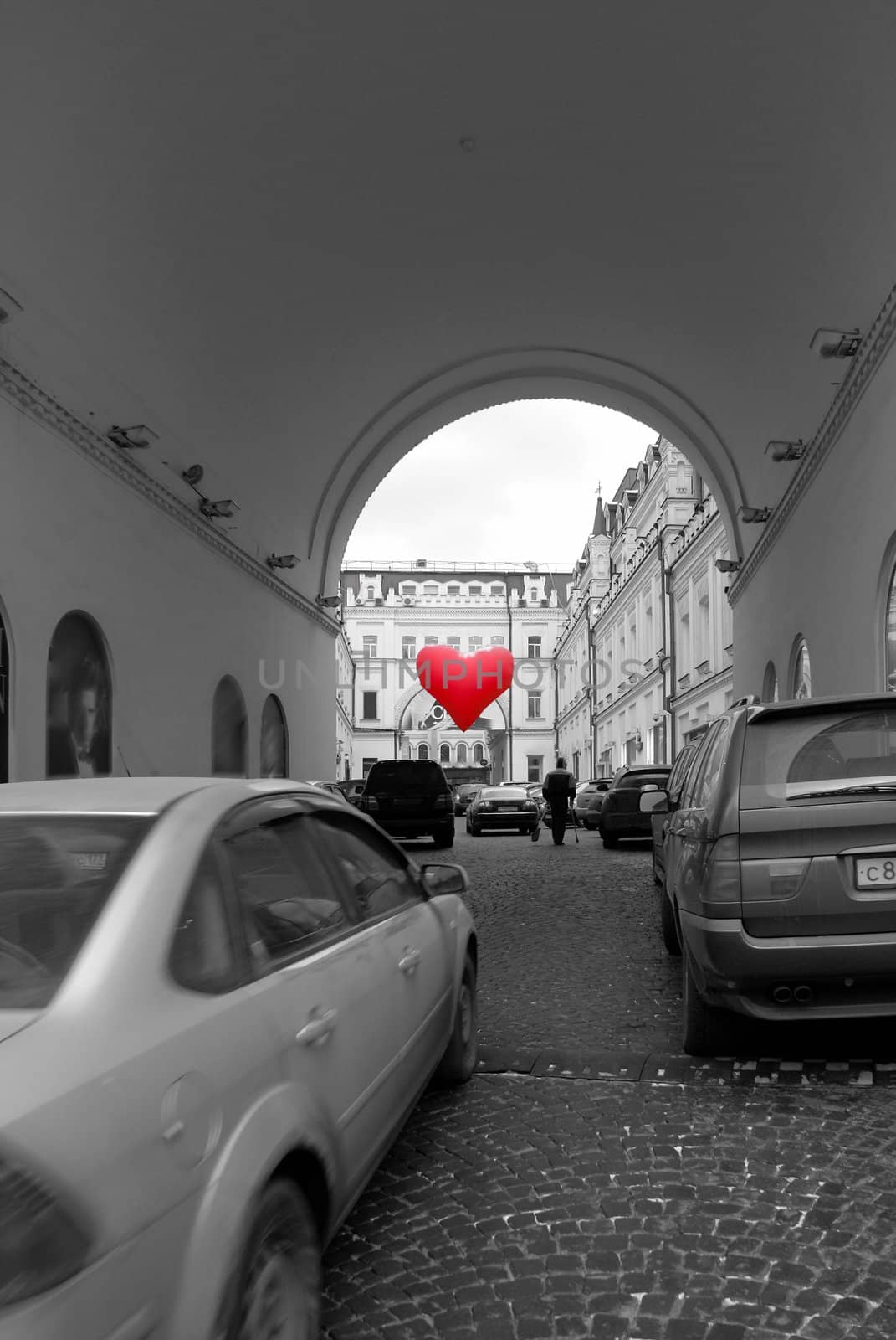 Big red heart ballon is hanging over old stree
