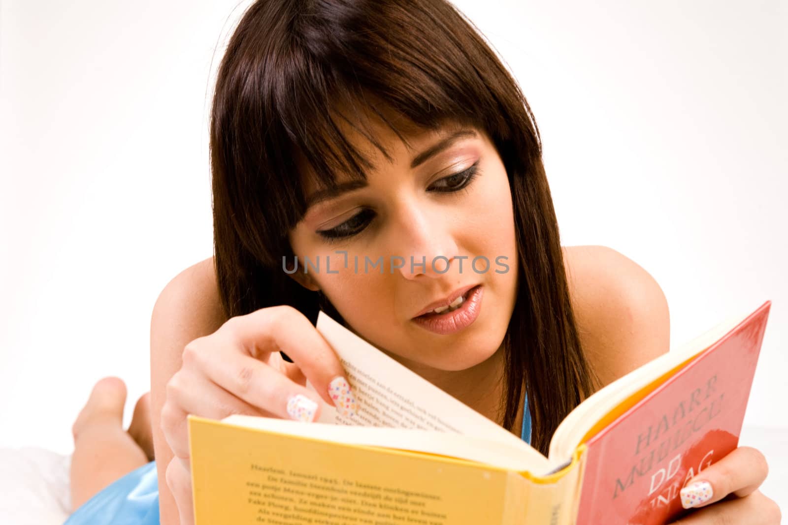 Brunette in pyjama's reading a book in bed.
Titles have been made unreadable so no copyright infrigment.