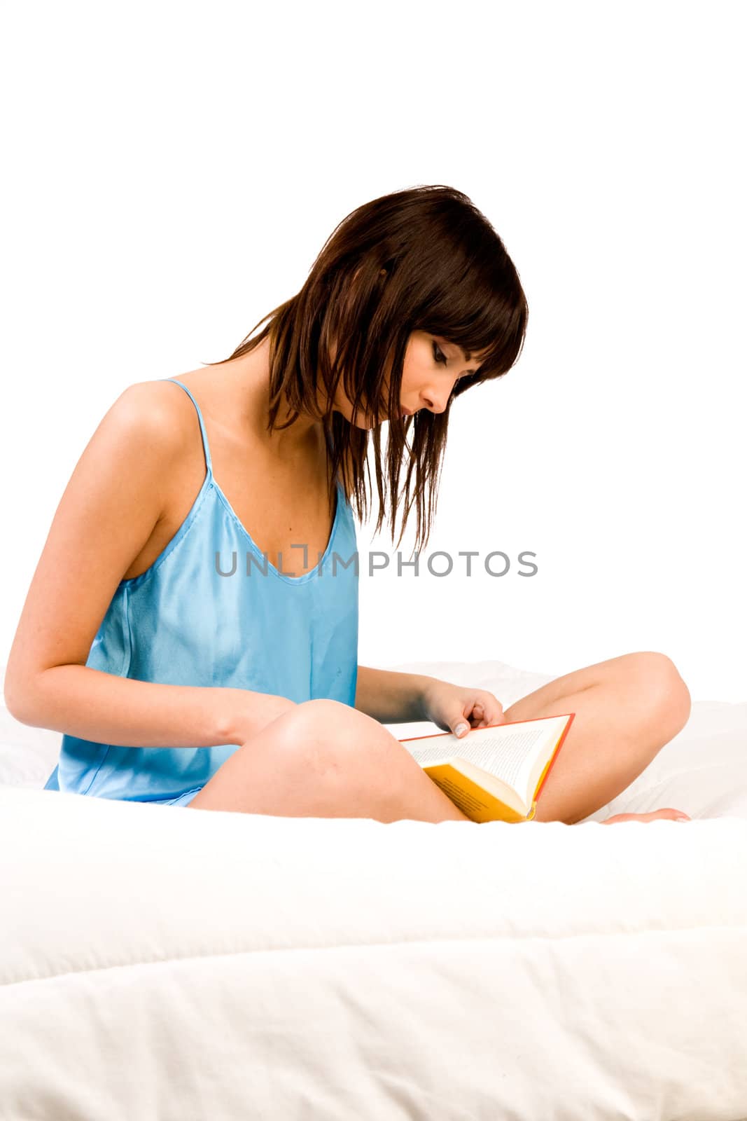 Brunette in pyjama's reading a book in bed