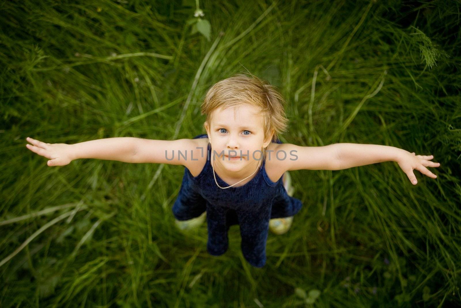 The girl looking upwards and standing on a grass
