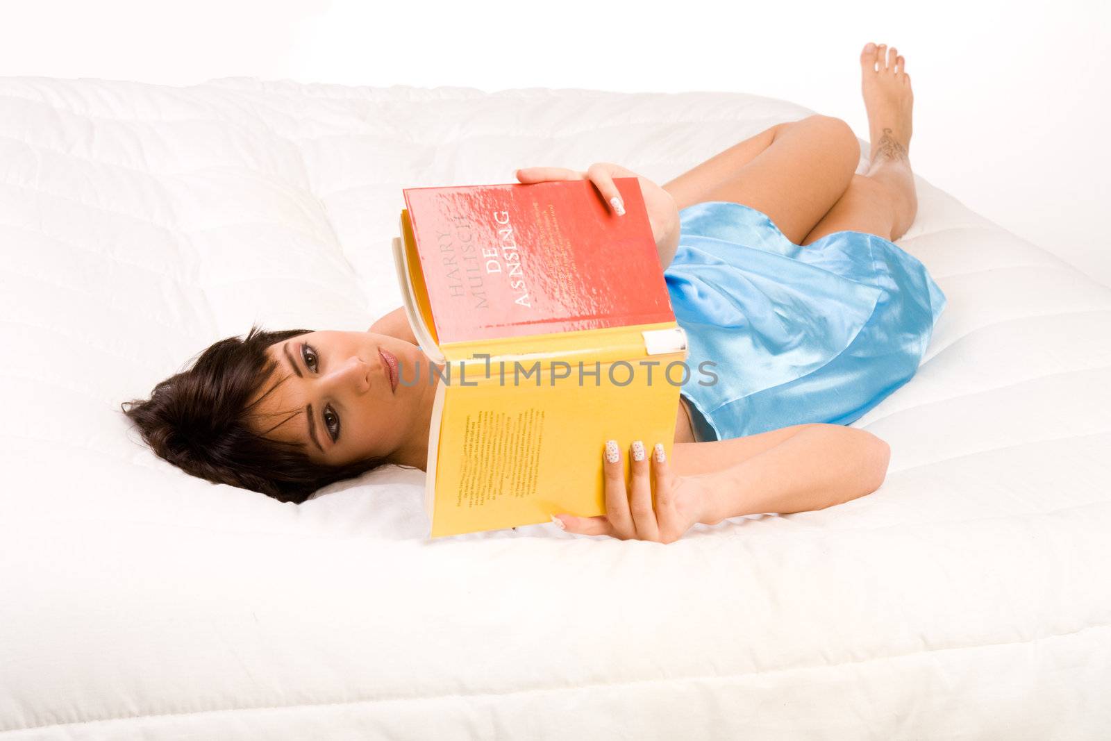 Brunette in pyjama's reading a book in bed.
Titles have been made unreadable so no copyright infrigment.