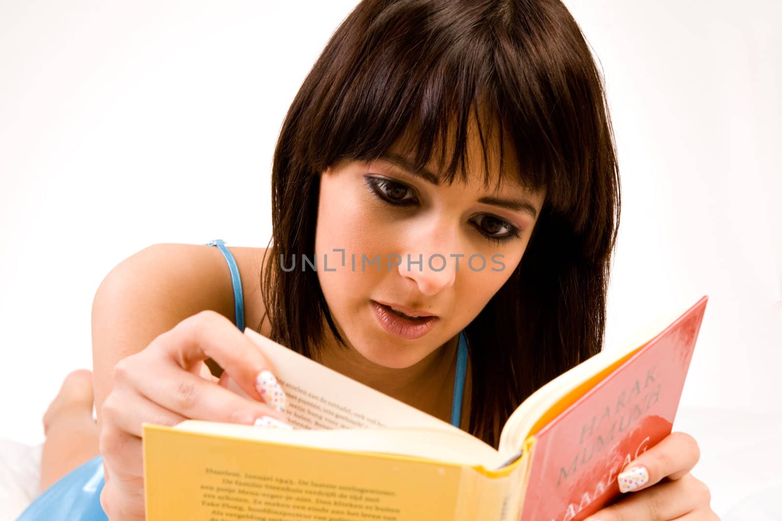 Brunette in pyjama's reading a book in bed.
Titles have been made unreadable so no copyright infrigment.