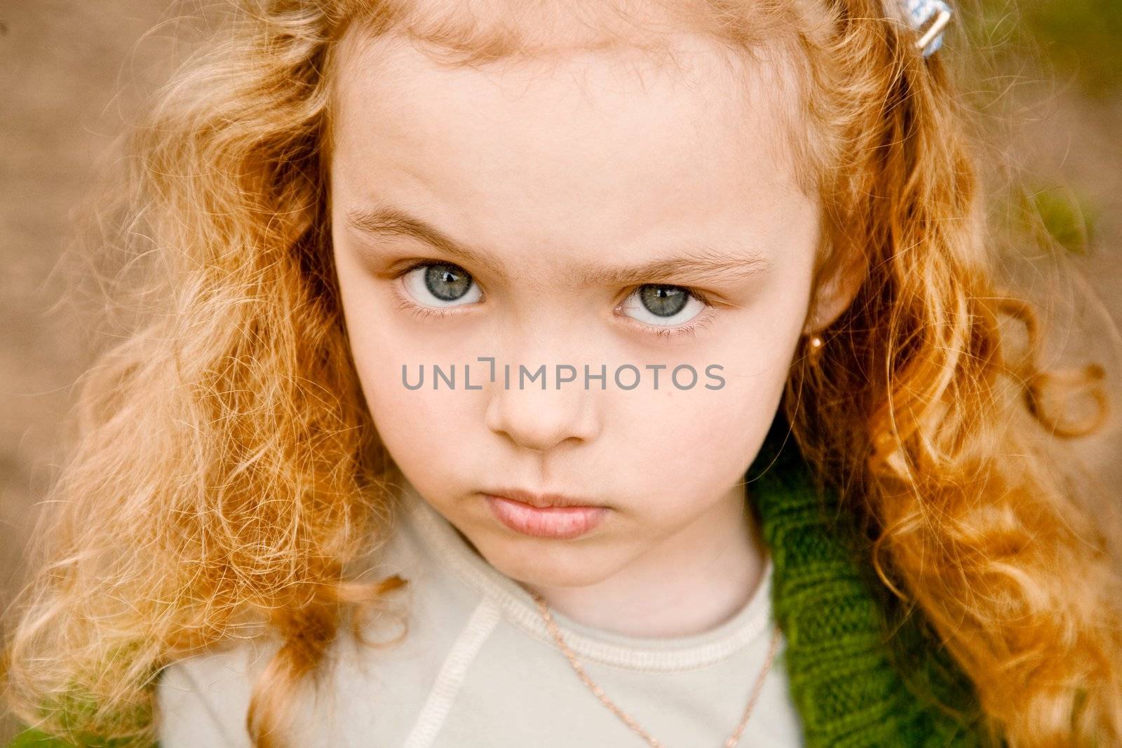 Portrait of the serious grey-eyed little girl with the long hair, looking in a shot
