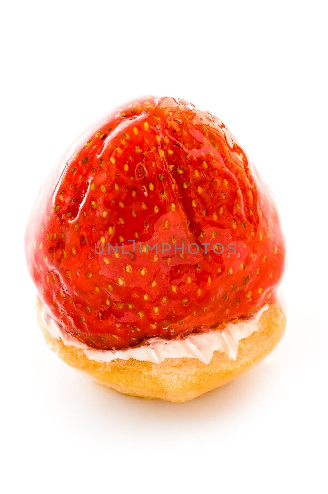 One small cake decorated with the big strawberry close up on a white background
