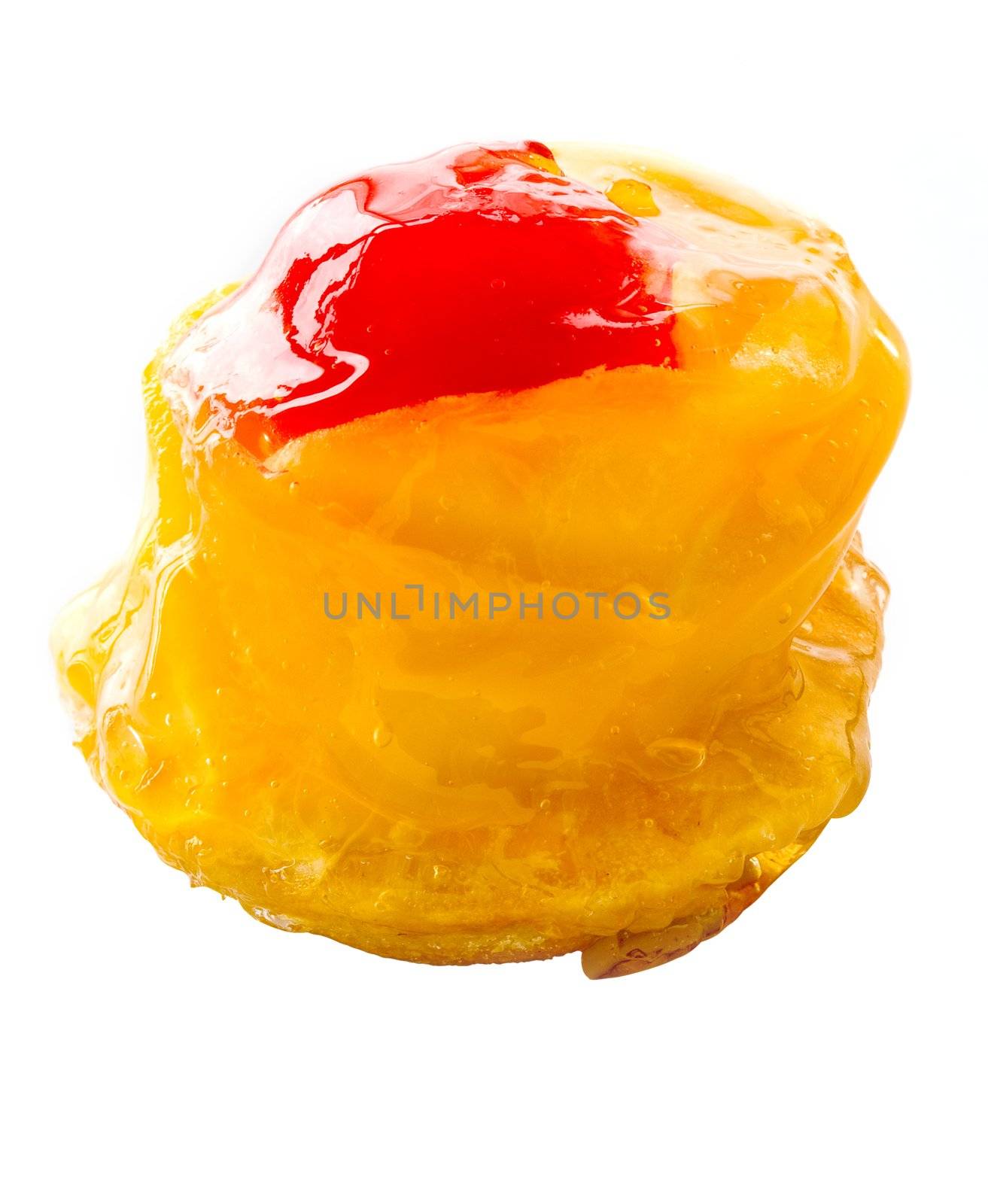 One small cake decorated with the a mango and a cherry close up on a white background
