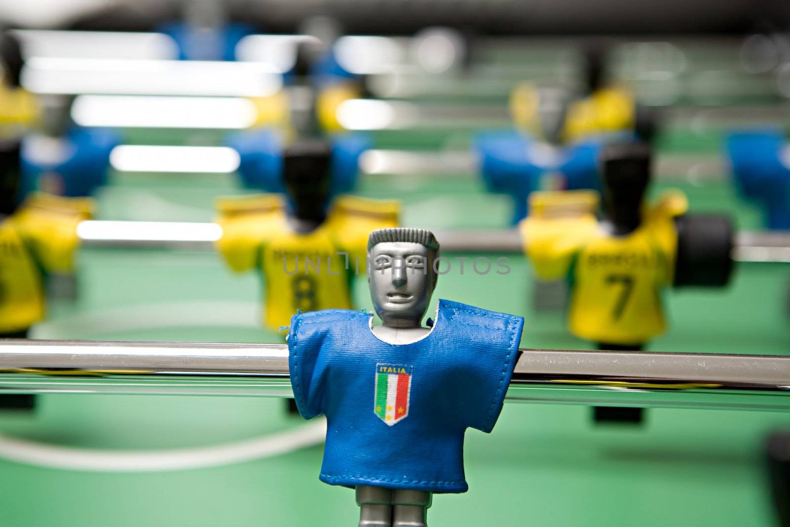 Image of desktop football with plastic players in the dark blue and yellow form close up on a green background
