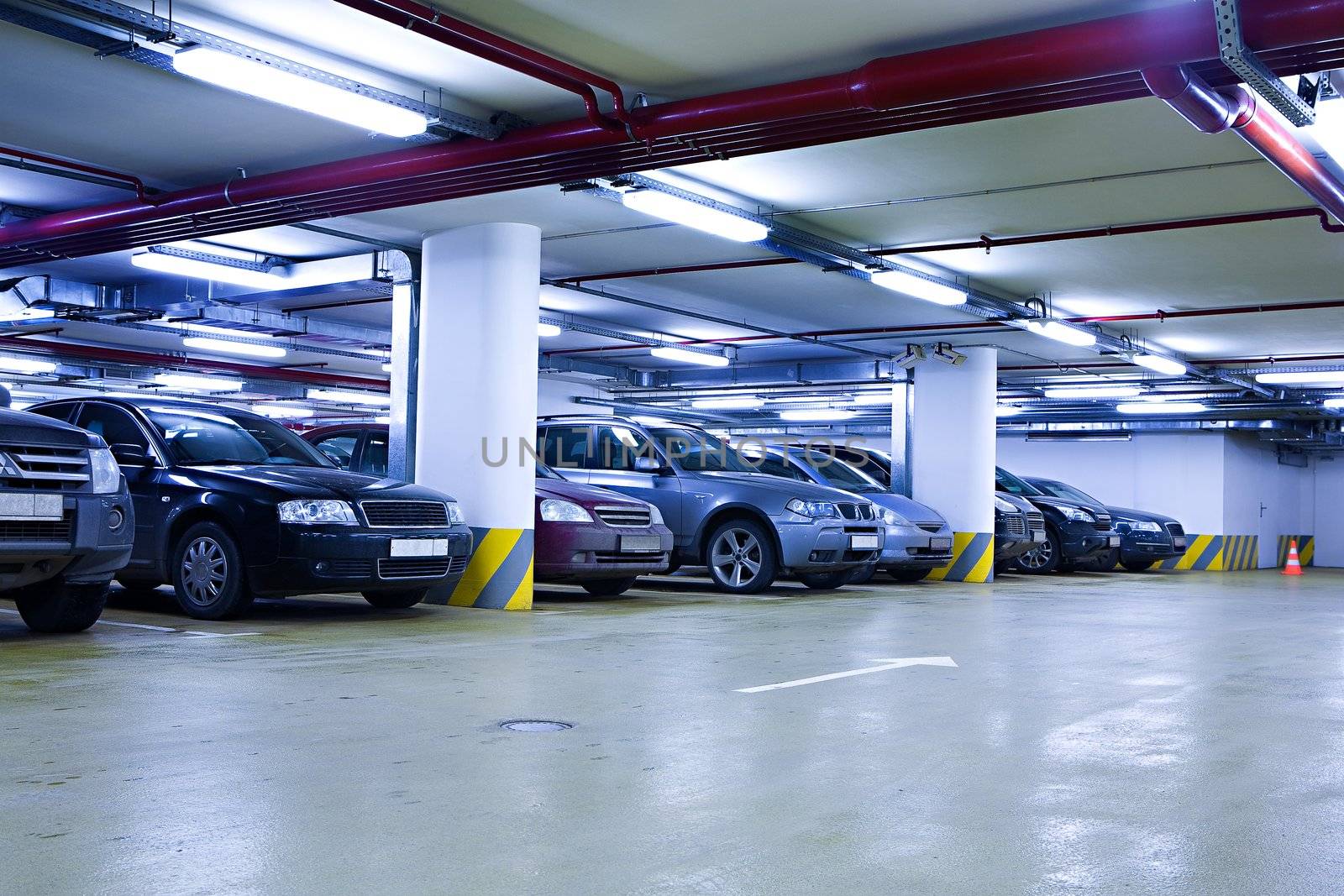 The shined underground garage with the moving cars and parked cars
