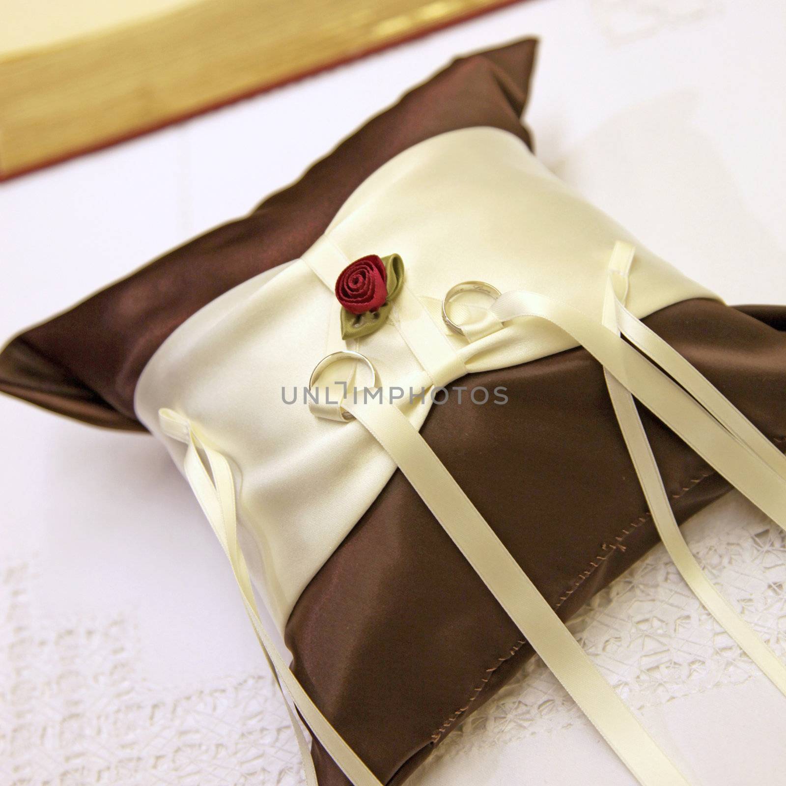 elegant ring pillows with wedding rings and sand - close up