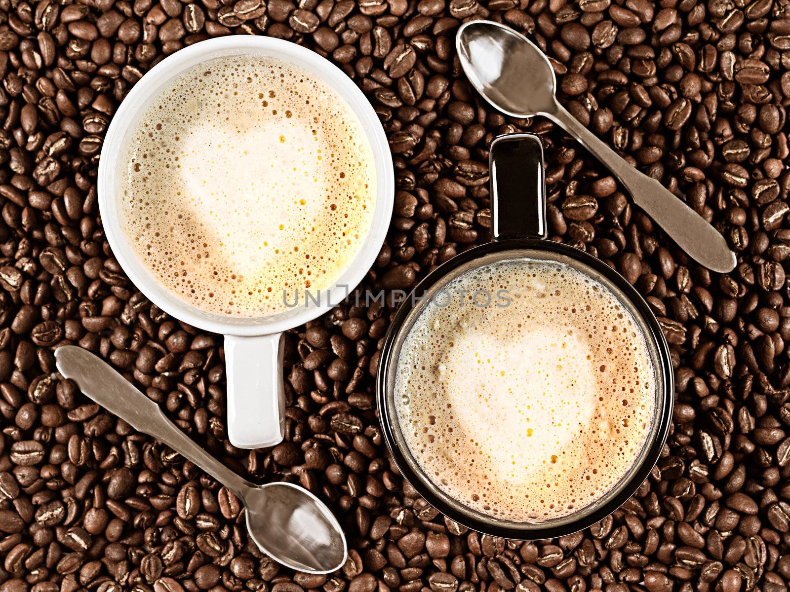 Two cups with Cafee Latte with heart shaped rosetta surrounded by coffee beans and spoons