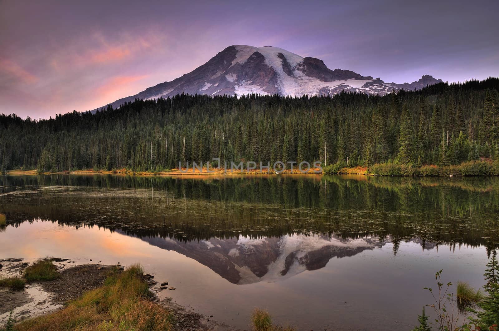 Mount Rainier reflected across the reflection lakes at dusk under a dramatic sky