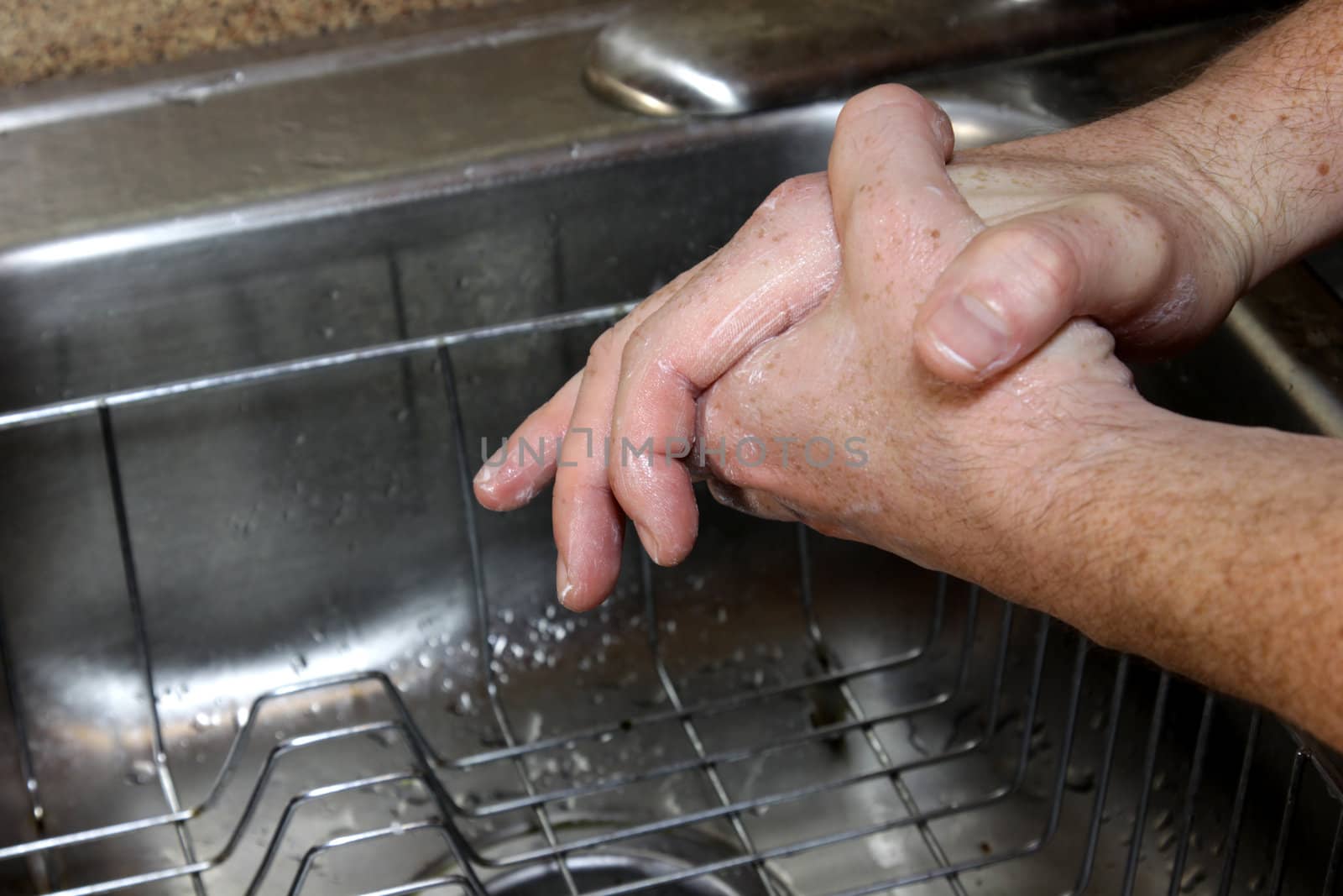 A man washing his hands with soup in a sink.
