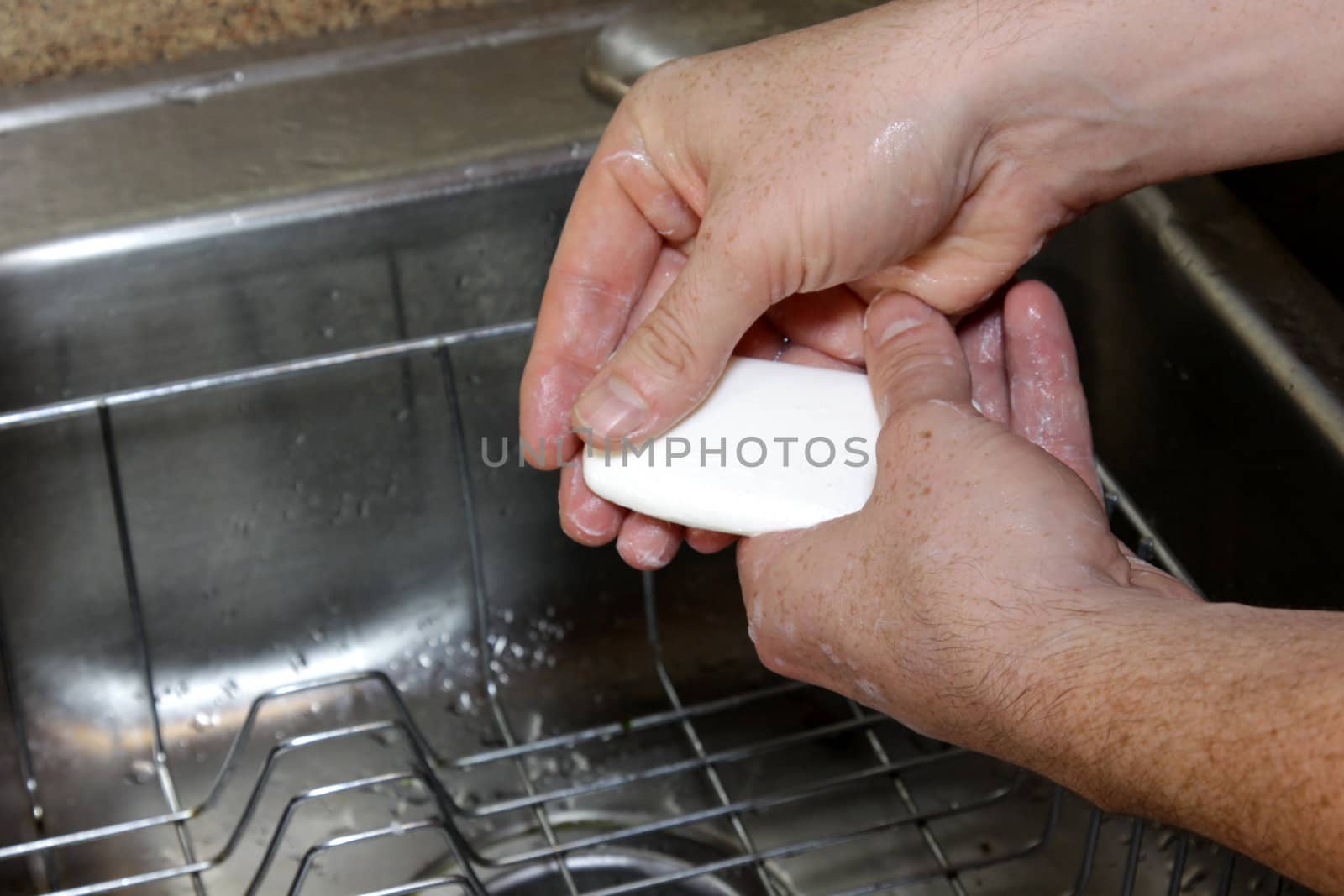 A man washing his hands with soup in a sink.
