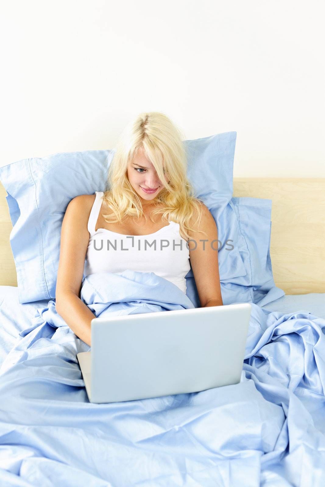 Woman sitting in bed with computer by elenathewise