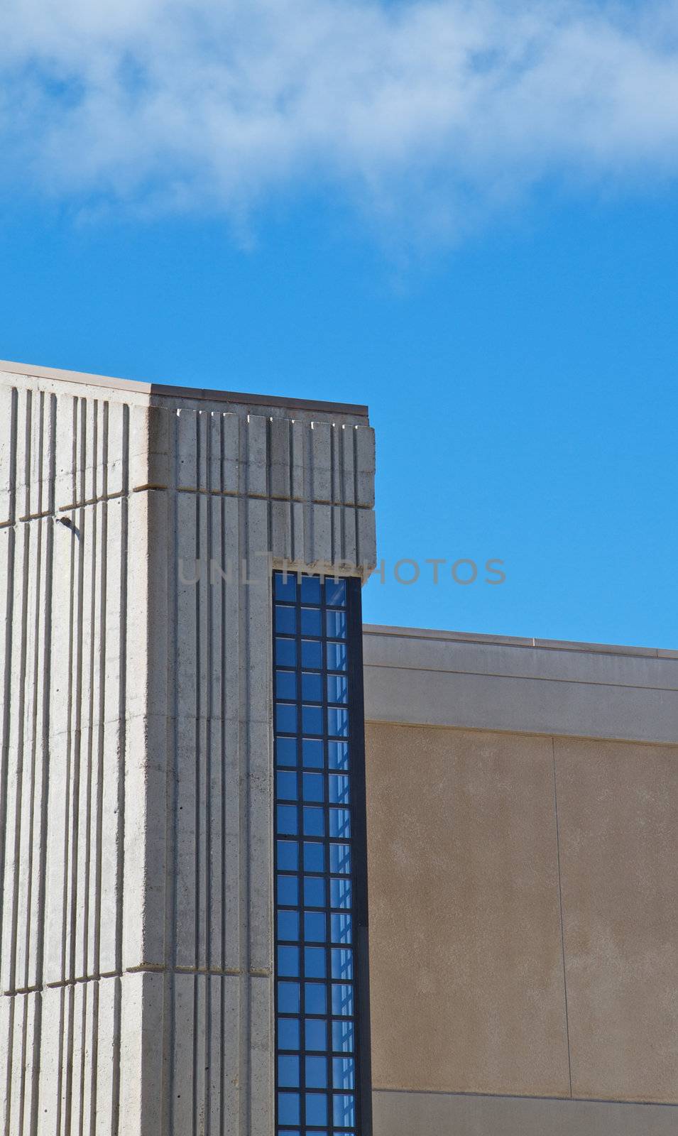 Vertical image of blue windowed concrete building with blue sky