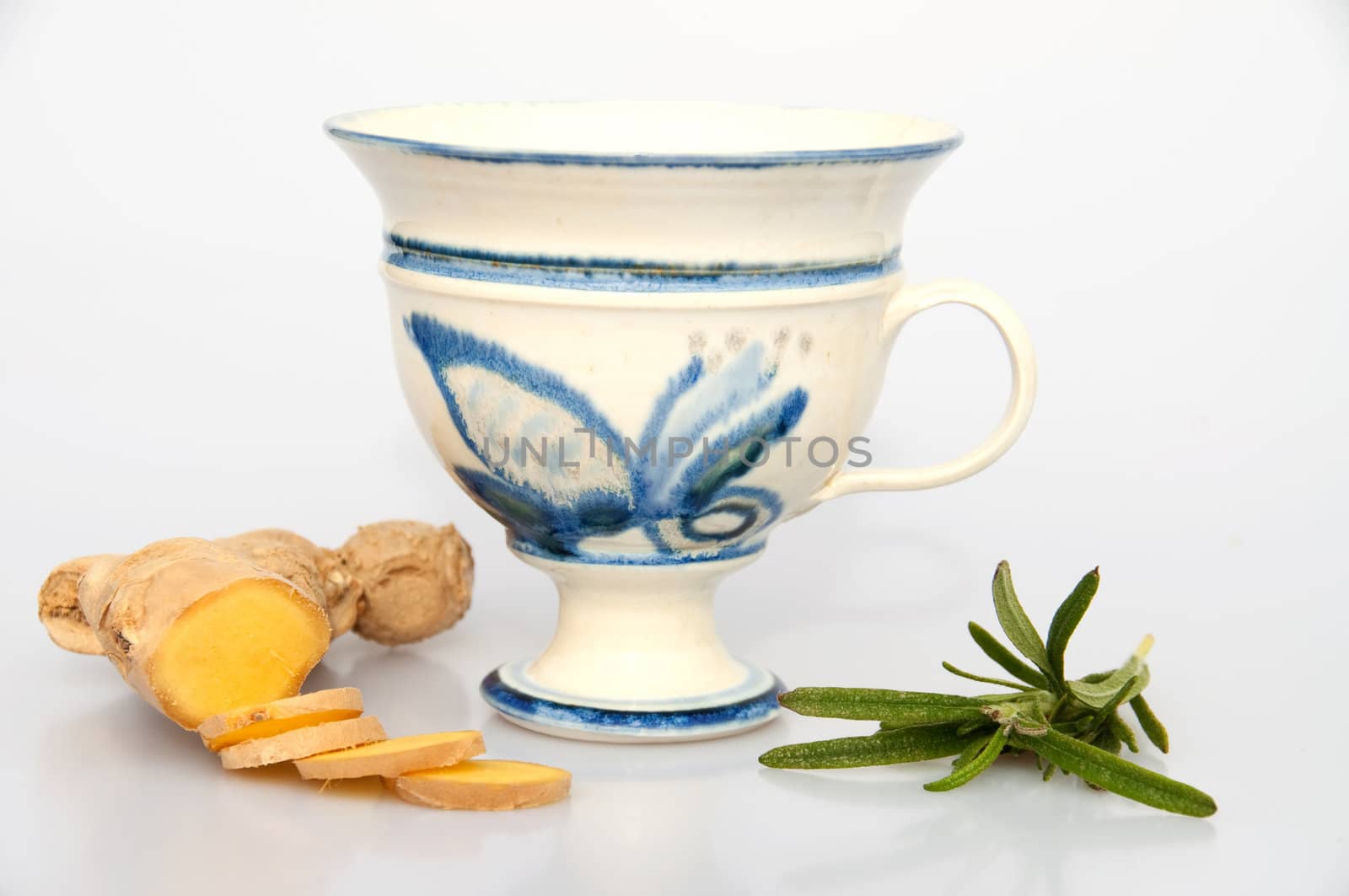 A teacup, fresh rosemary and ginger. isolated