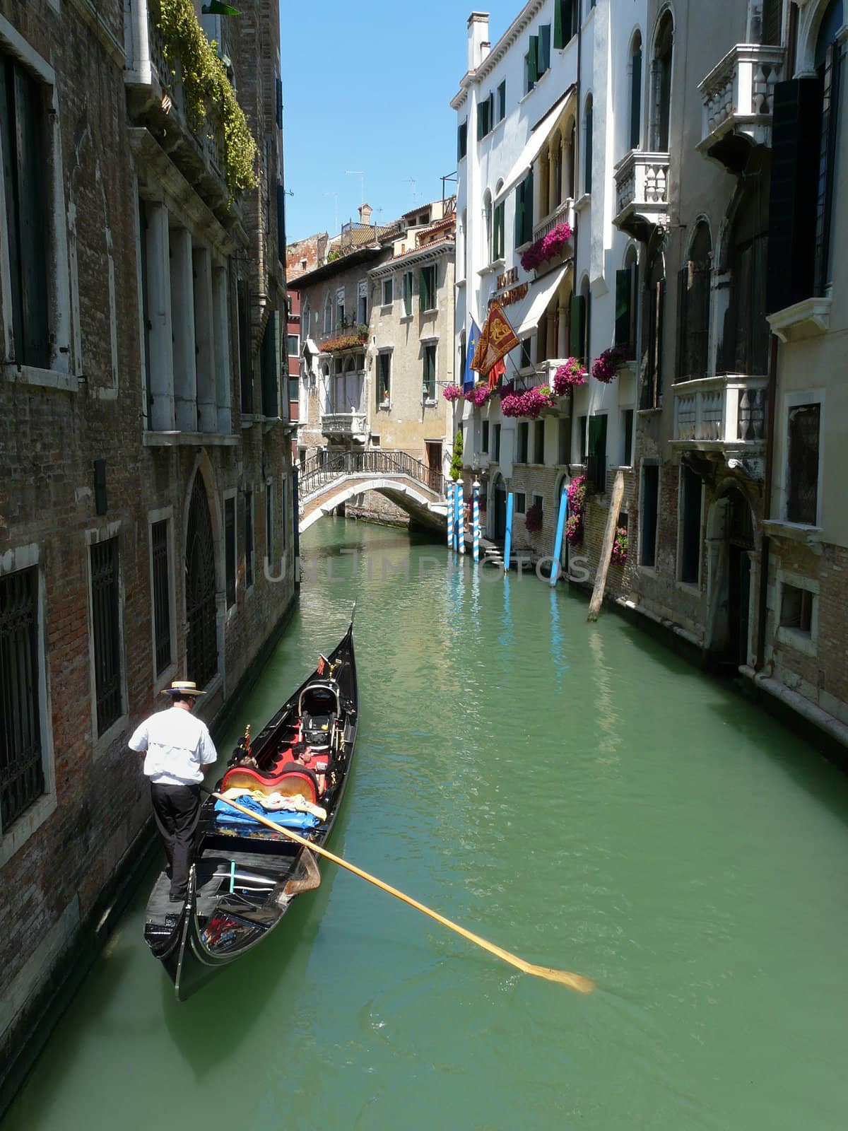 Gondolier paddling his gondola through a small channel in Venice, Italy.
