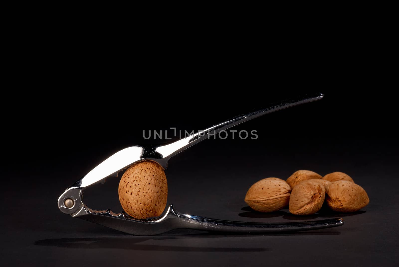 Still life: silver nutcracker and a heap of almonds