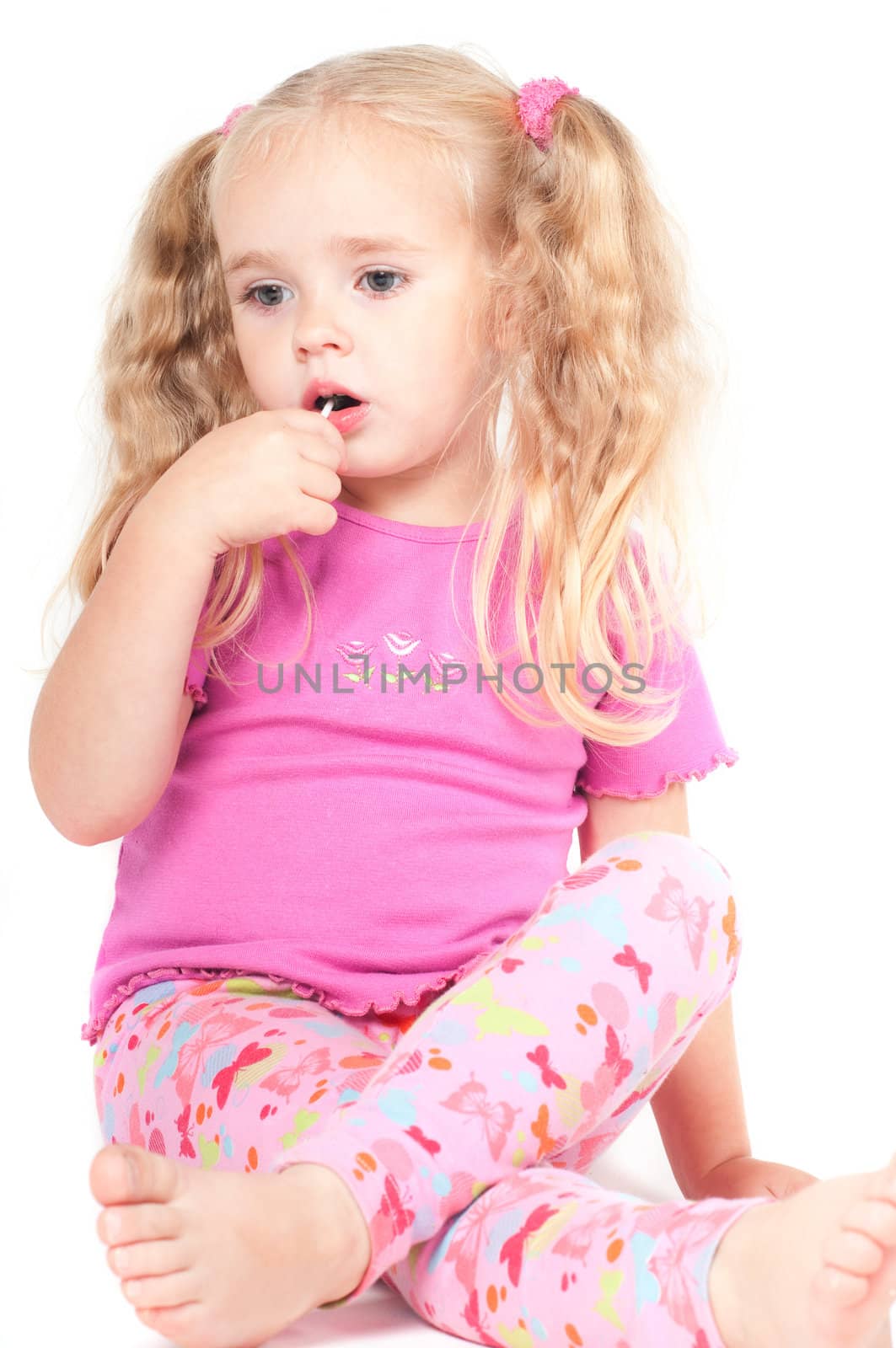 Little cute girl in pink and with ponytails in studio