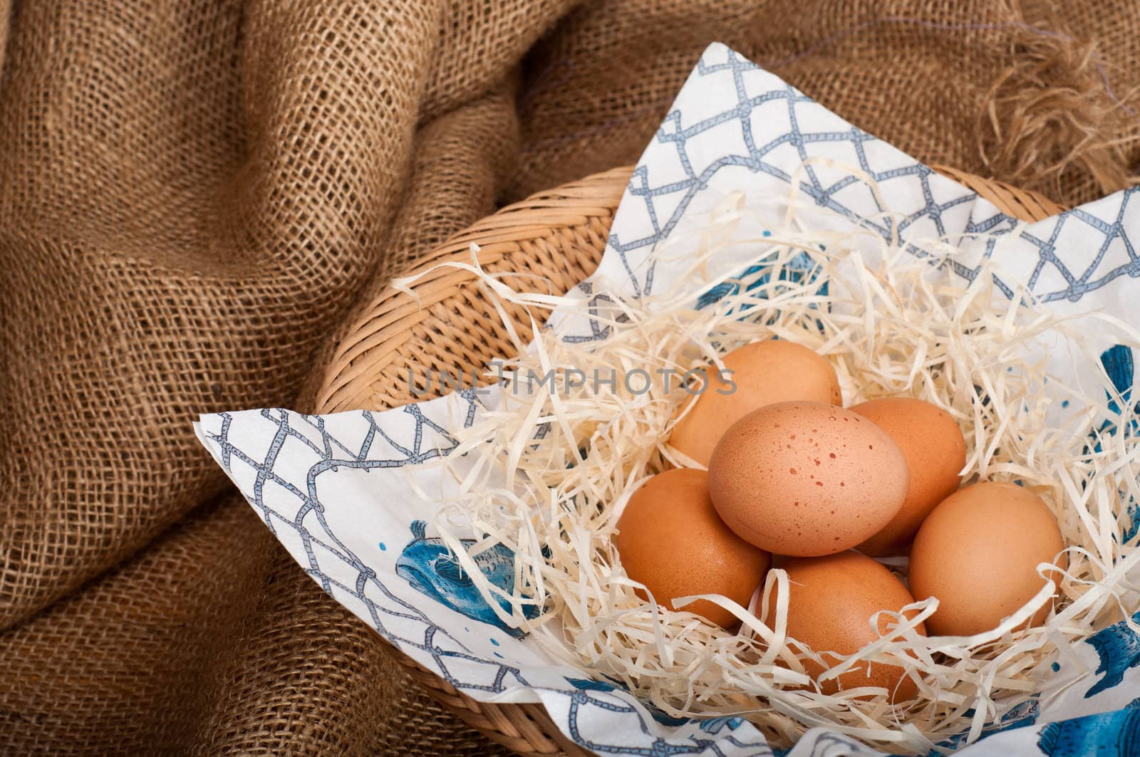 Fresh farm eggs in a basket on a hessian background