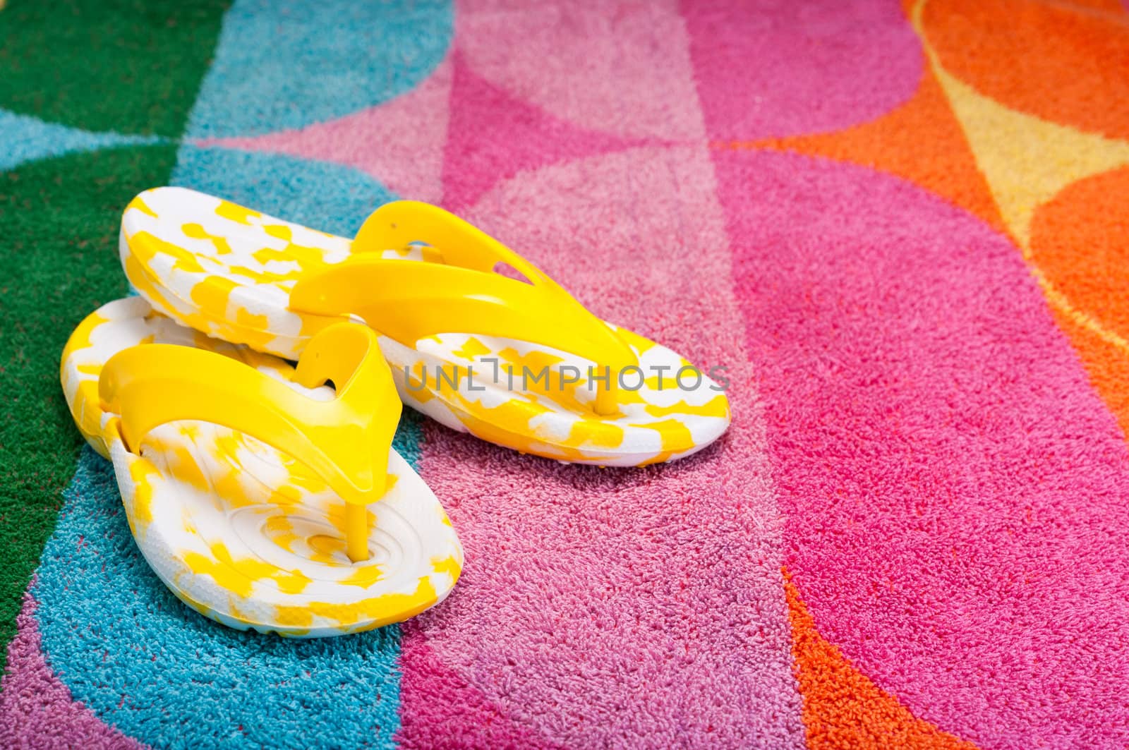 Bright yellow flip-flops on a colorful beach towel