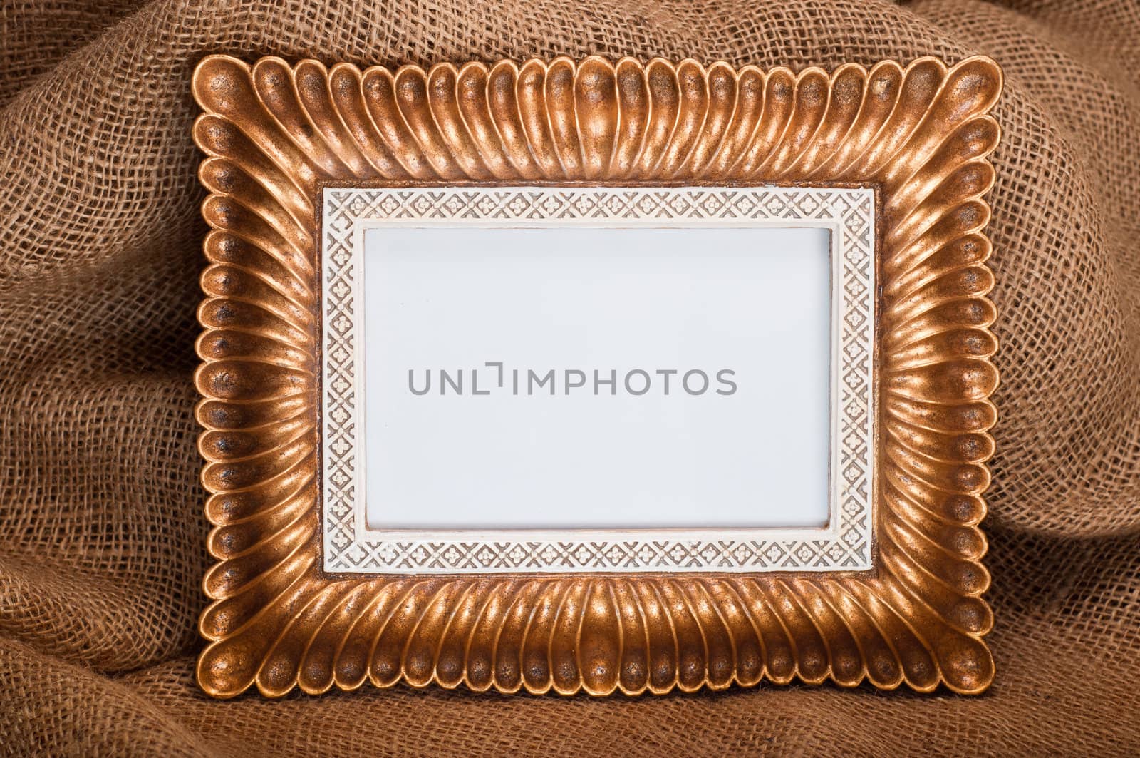 Beautiful ornate golden picture frame on hessian background