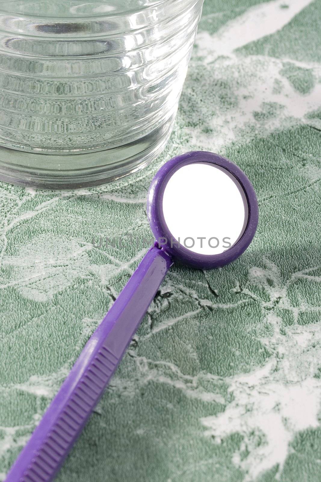 Purple dental mirror on the green countertop.